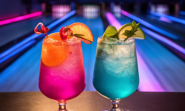 Zwei farbenfrohe Cocktails auf einem Tisch mit Bowlingbahn im Hintergrund