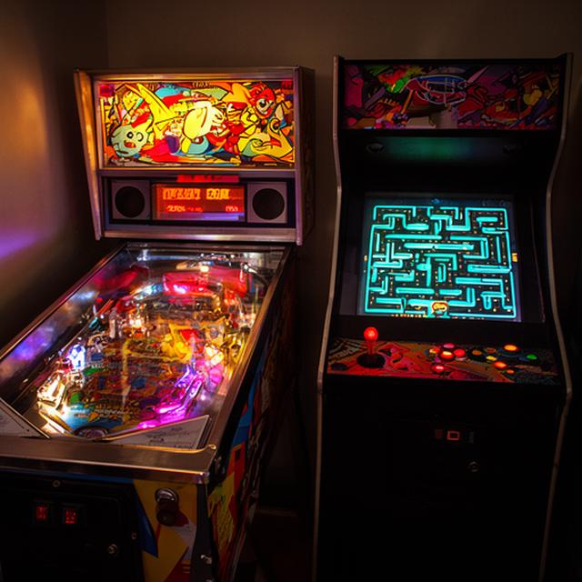 Retro-Flipper und Pac-Man-Automat mit bunten Lichtern in der Spielehalle